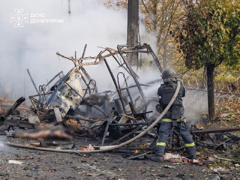 Firefighters at the burnt-out bus — graphic aftermath, blurred