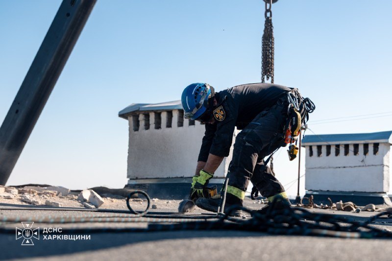 Rescuer-climbers work on the roof of the damaged building